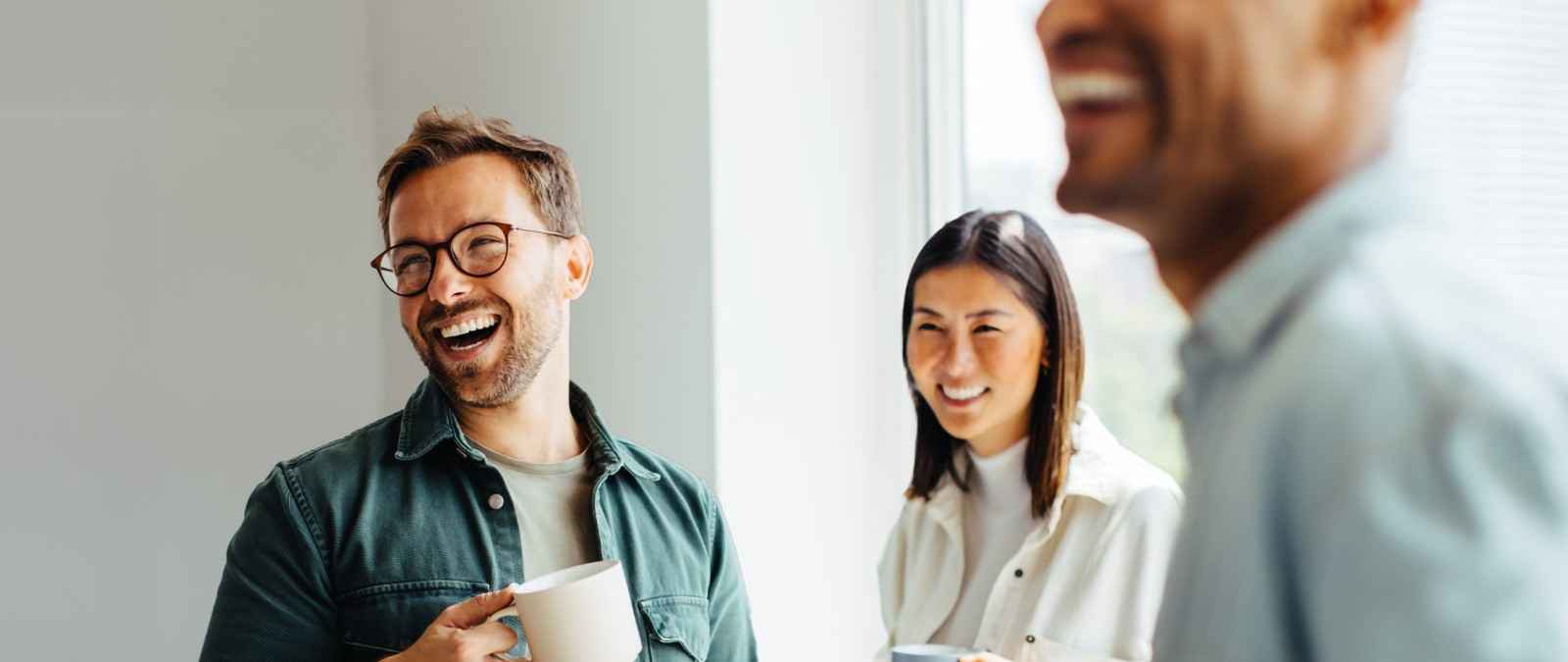 Gothaer Direktversicherung GarantieRente Invest: Kollegen freuen sich bei einer Tasse Kaffee über ihre arbeitgeberfinanzierte Altersversicherung.